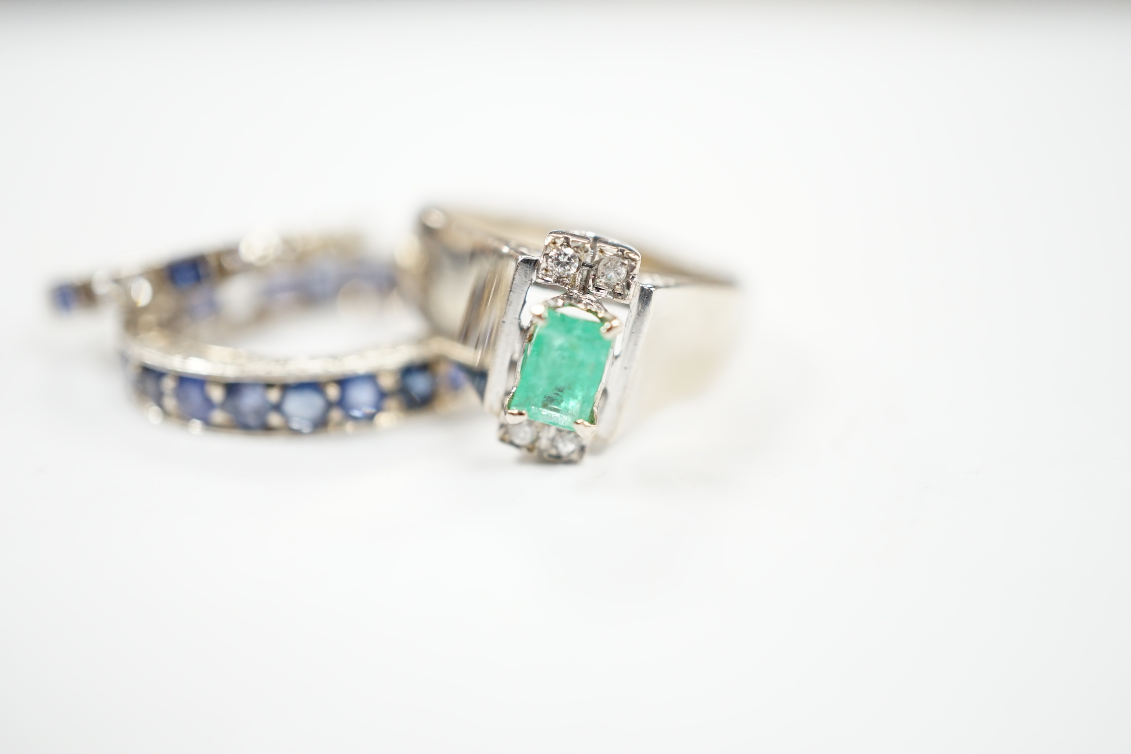 An 18k white metal, emerald and diamond set dress ring, size O, a white metal and sapphire set full eternity ring (stones missing) and an 18ct, sapphire and diamond set half hoop ring, gross weight 10 grams.